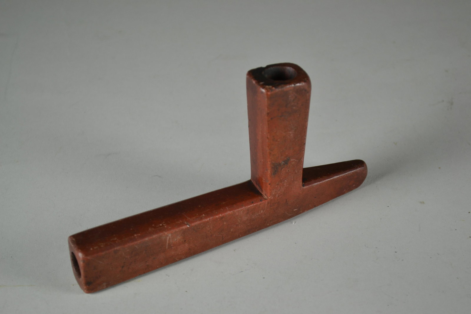 Late 19th Century Lakota T Pipe: made of catlinite. Shows signs of heavy use with multiple scratches and a few small chips. Signed in script on bottom. 3" h x 6" l