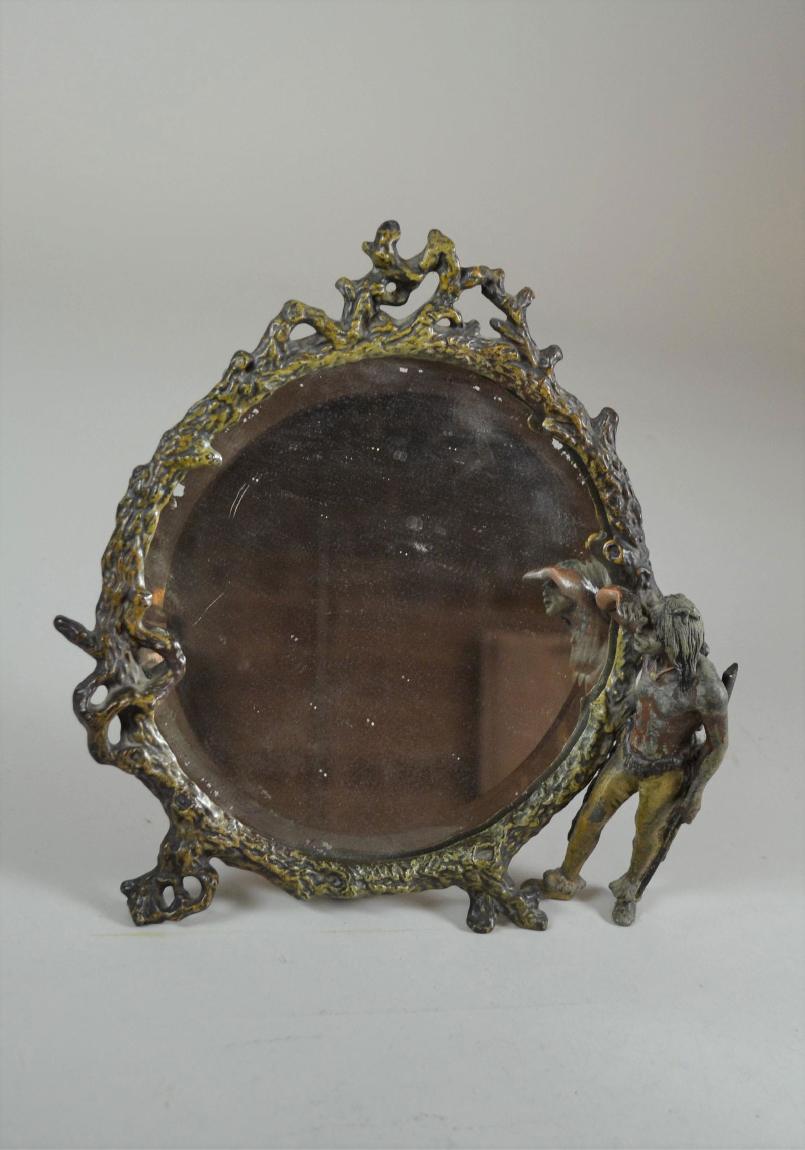 Late 19th Century Mirror: with Indian figure. Wood figural painted iron frame with painted Spelter Indian with rifle attached to side. Figure has about 50% paint. Mirror has some silver loss. 10" h x 10" w.