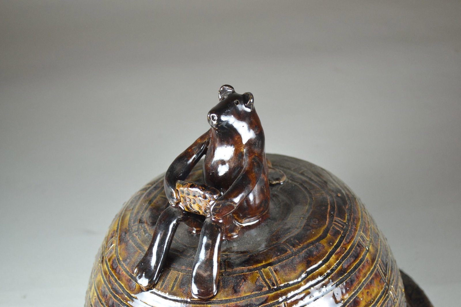 Claude Miller Art Pottery of a Bear Eatting Honey on a: signed and dated 2010. Has large firing crack in base. Otherwise in excellent condition. 10" h x 11" dia