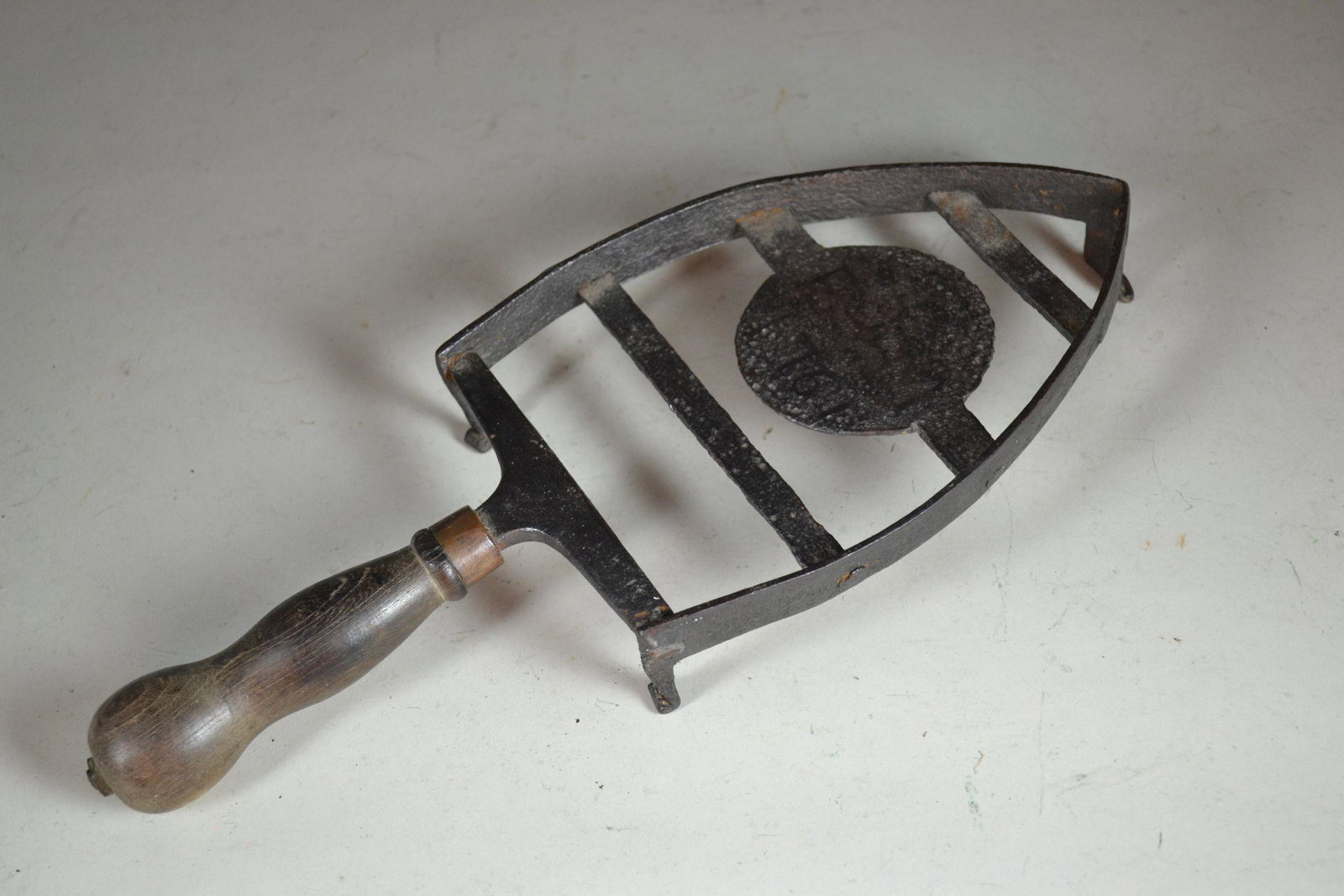 18th Century Signed Trivet: marked E.T. M. or T.E.M. 1761. Wrought iron and wood handle, excellent condition. From the Old Salem area of North Carolina. 1 1/2" h x 5" w x 12" d.