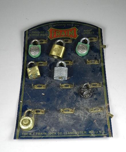 Fraim Tin Padlock Display: includes 7 locks, 4 are Fraim. Only small eagle lock has key. Several dents and areas of paint loss. 18" h x 11" w