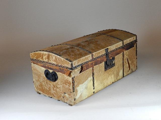 Hide Trunk Lined with 1817 Dated Newspaper: has several splits, period repair to back side. Hide still retains most of its hair. Shaped iron handles on ends, lock is present, missing dust cover. Fully lined with newspaper dated June 28, 1817. B