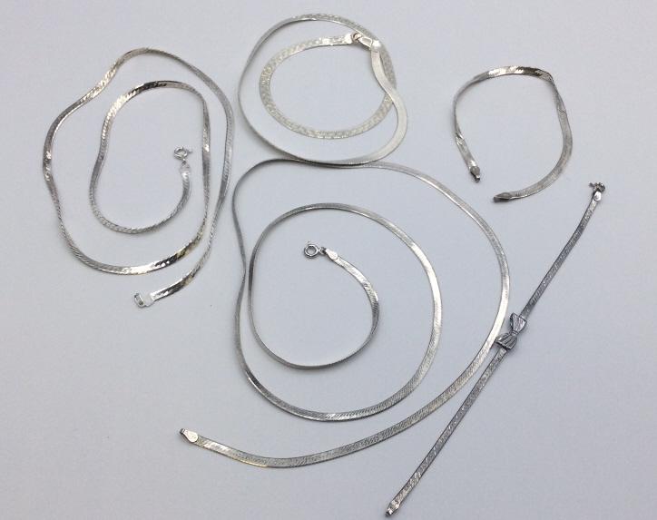 Five Pieces Sterling Herringbone Jewelry: 29 inch chain. 24 inch chain. 18 inch chain. 8 inch bracelet with some kinks and no clasp. 7 inch bracelet with bow. Good condition.