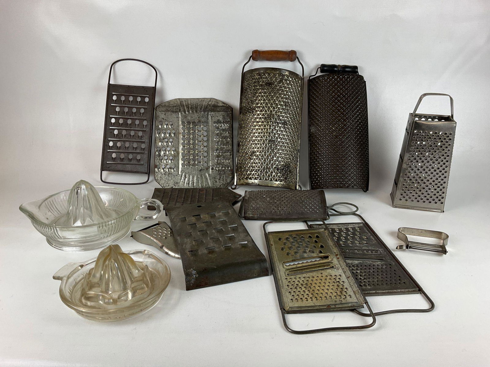 Graters and Reamers: Two glass reamers, Easley's is badly chipped. Along with an assortment of tin or metal graters. All with wear. Tallest with wooden handle is 11.5 inches.