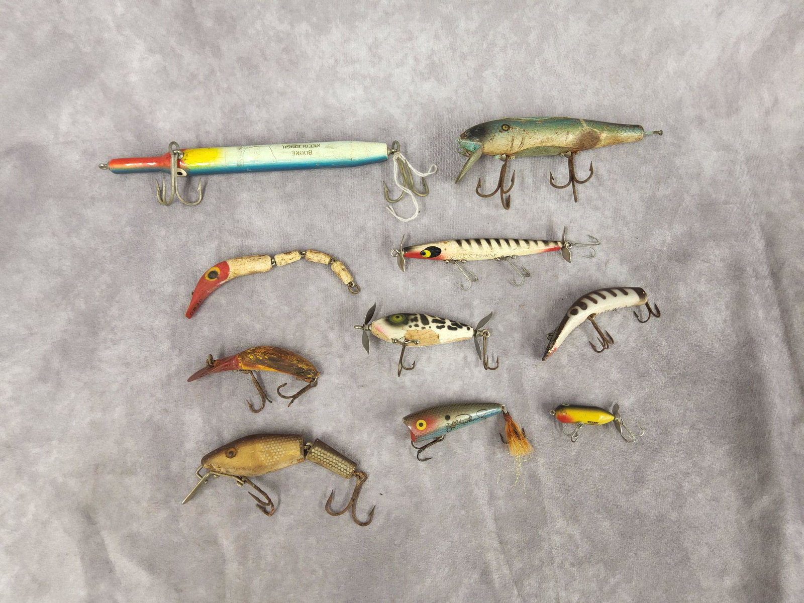 Vintage Fishing Gear Ten Branded Lures: Considerable wear with some hooks tarnished or missing as seen in photos. Measure 2.25 inches to 7.5 inches long. Includes Boone Needlefish, Lazy Ike, Teeny Torpedo, and more.