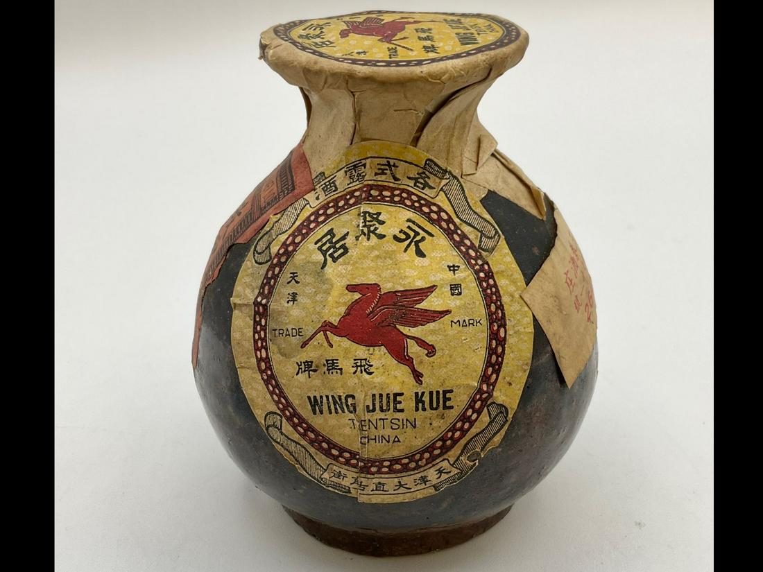 Vintage Ceramic Chinese Medicine Bottle: Paper labels with red Pegasus. Marked Wing Jue Kue. Stains to paper. 3 inches wide x 3.5 inches tall.