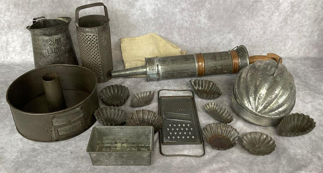 Group of Tin Kitchen Collectibles: Includes sausage stuffer, molds, Swans Down cake pan, graters, etc. wear from use with some rust. Handle on sausage stuffer is damaged. Largest 20” long.