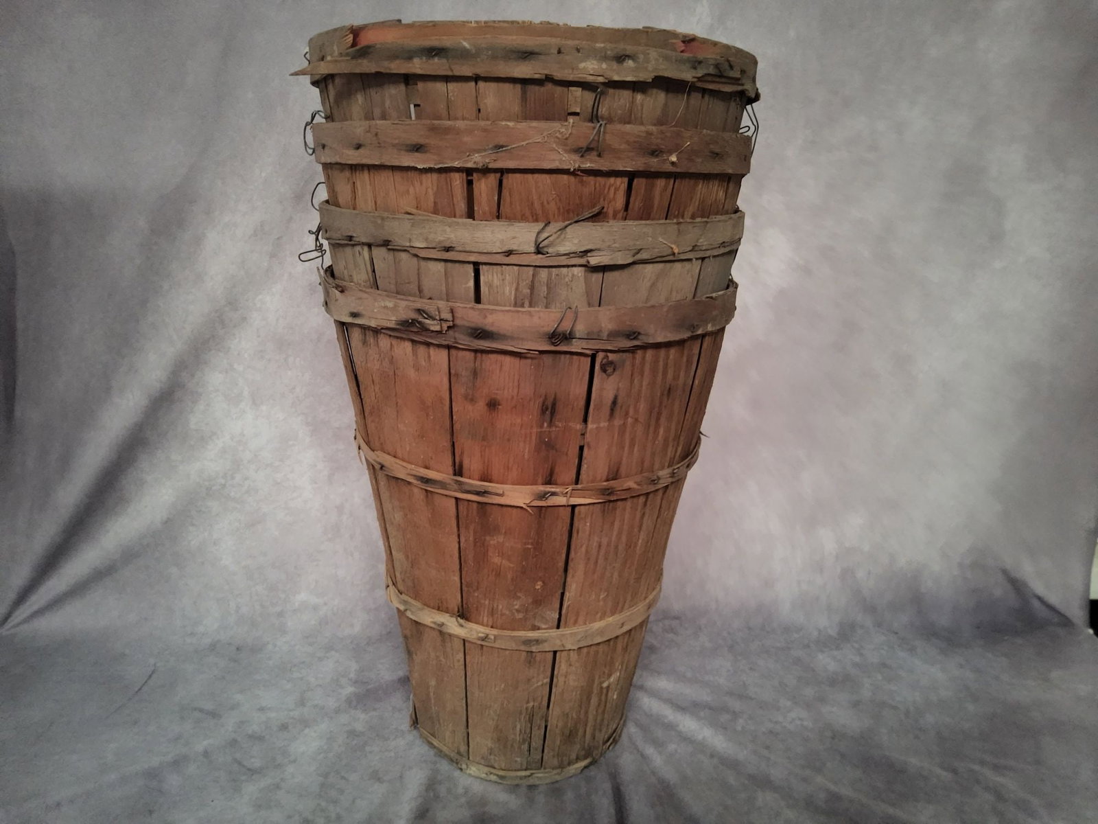 Four Tall Wooden Bushel Baskets: Good condition overall with expected wear as seen in photos. Baskets measure 20 inches tall and 15 inches in diameter at the top.