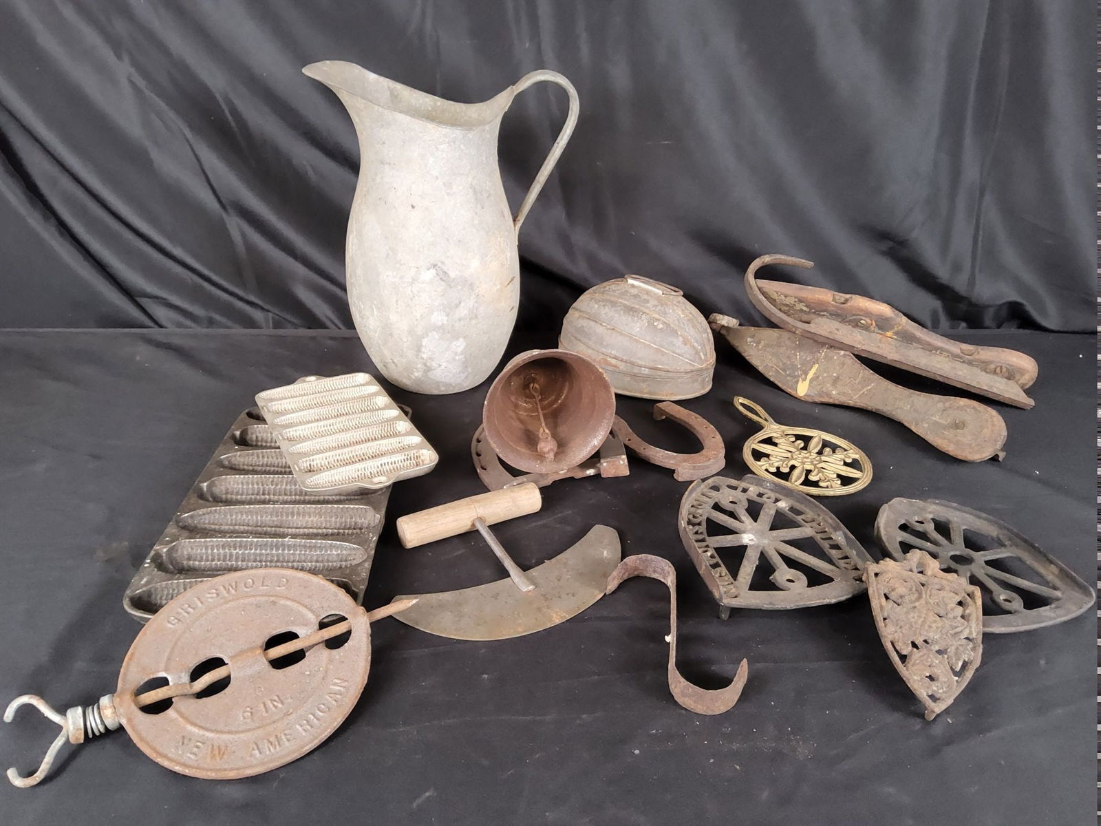 Cast Iron Primitives and More: Includes Griswold stove eye, corn dodger pans, trivets, chopper , melon mold, ice skates. Pitcher is 12 inches tall. Fair condition.