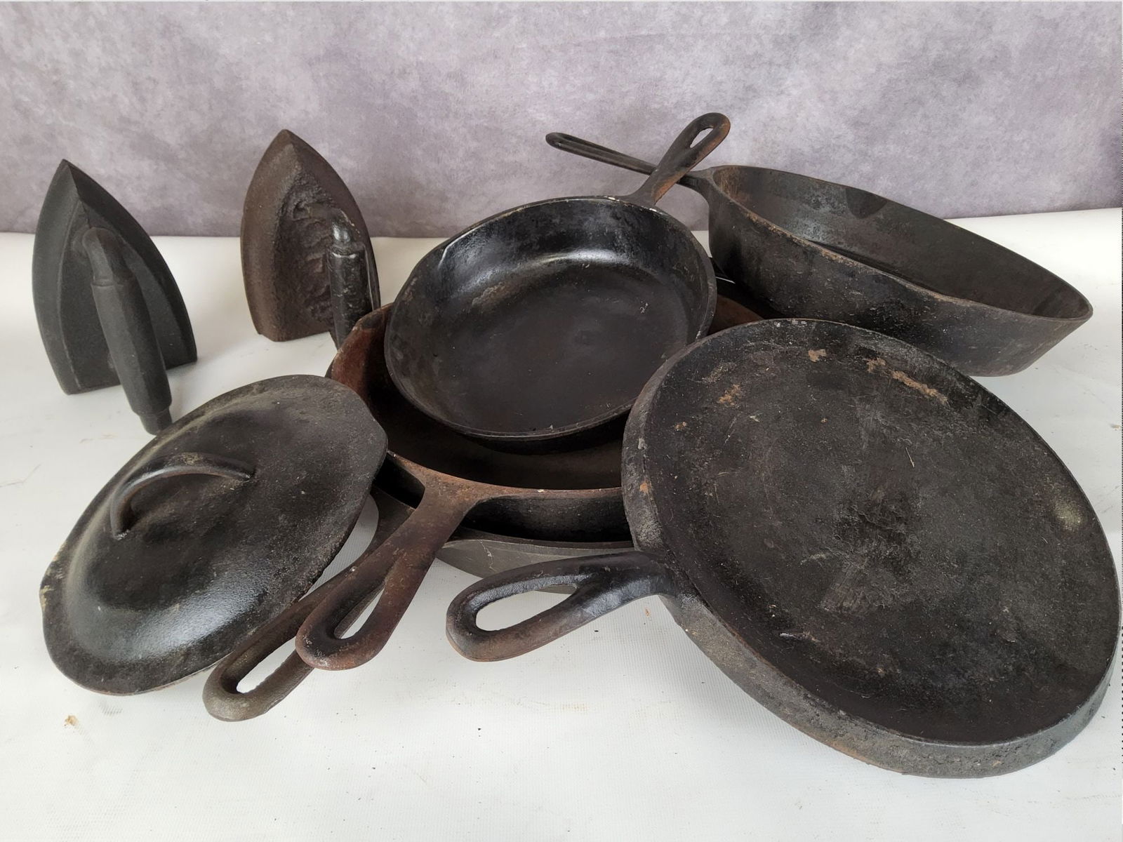 Cast Iron Skillets and Sad Irons: Lodge 12.5 inch skillet. Also unmarked 8.5 11 inch, #8 11 inch skillet, #5 8.5 inch. 10 inch griddle. 8 inch lid. #7 sad iron. All have rust and pitting . Overall fair to good condition.