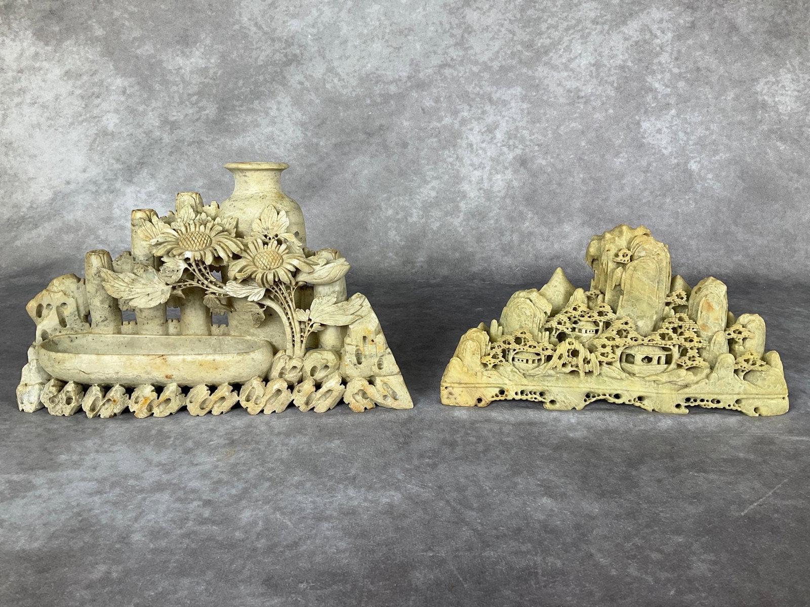 Two Soapstone Carvings: Larger carving is for use as an artists brush washer with flower design, and has one petal broken off. Smaller is a mountainscape in good condition. Dimensions of largest 11.5 x 2.5 x 6.75 inches.