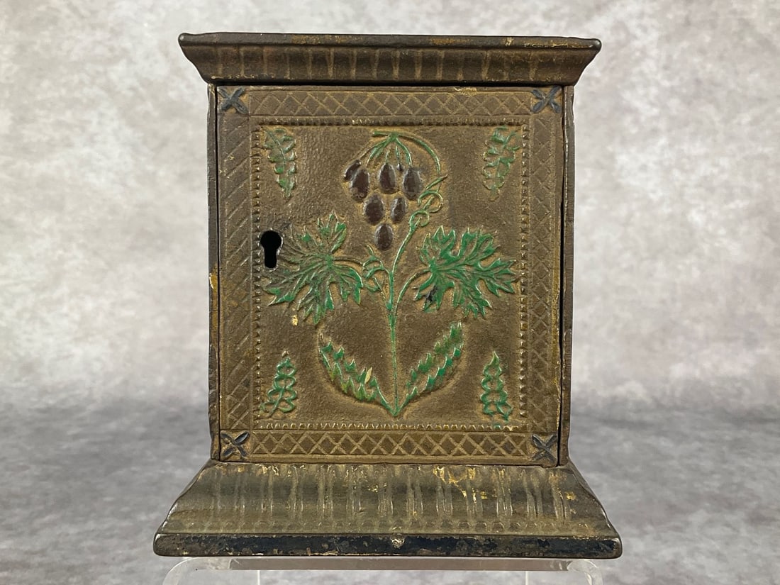 Cast Iron Floral Still Bank: Attributed to J and E Stevens. Four sides plus the top have original painted embellishments on the floral design. Bank is locked without a key. 4.25 inches wide x 4.25 x 4.75 inches tall. Good with mo