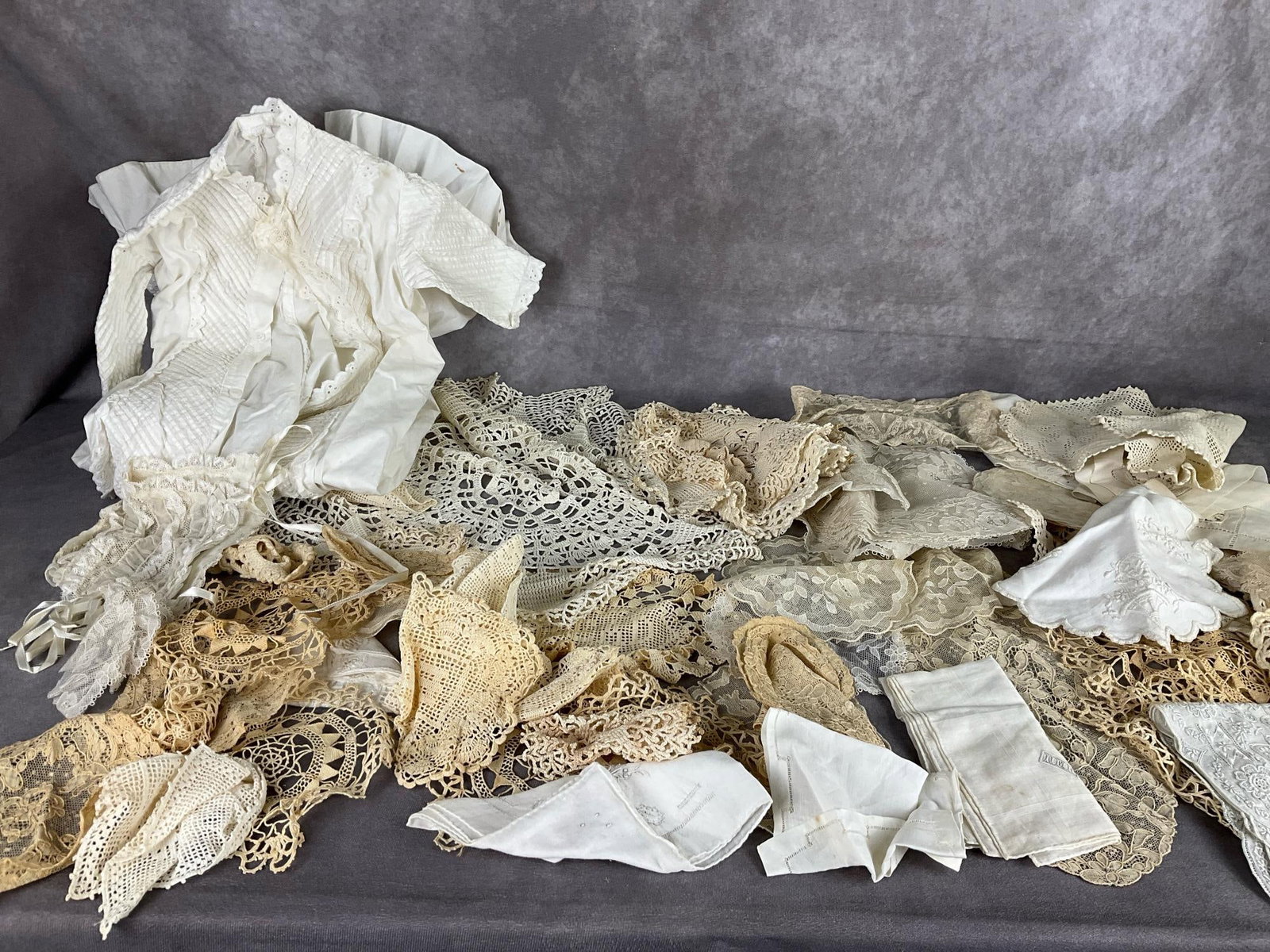Linen and Lace: Variety of lace doilies, handkerchiefs, and a hand worked baby cap with dress. Yellowing to many pieces but otherwise good.