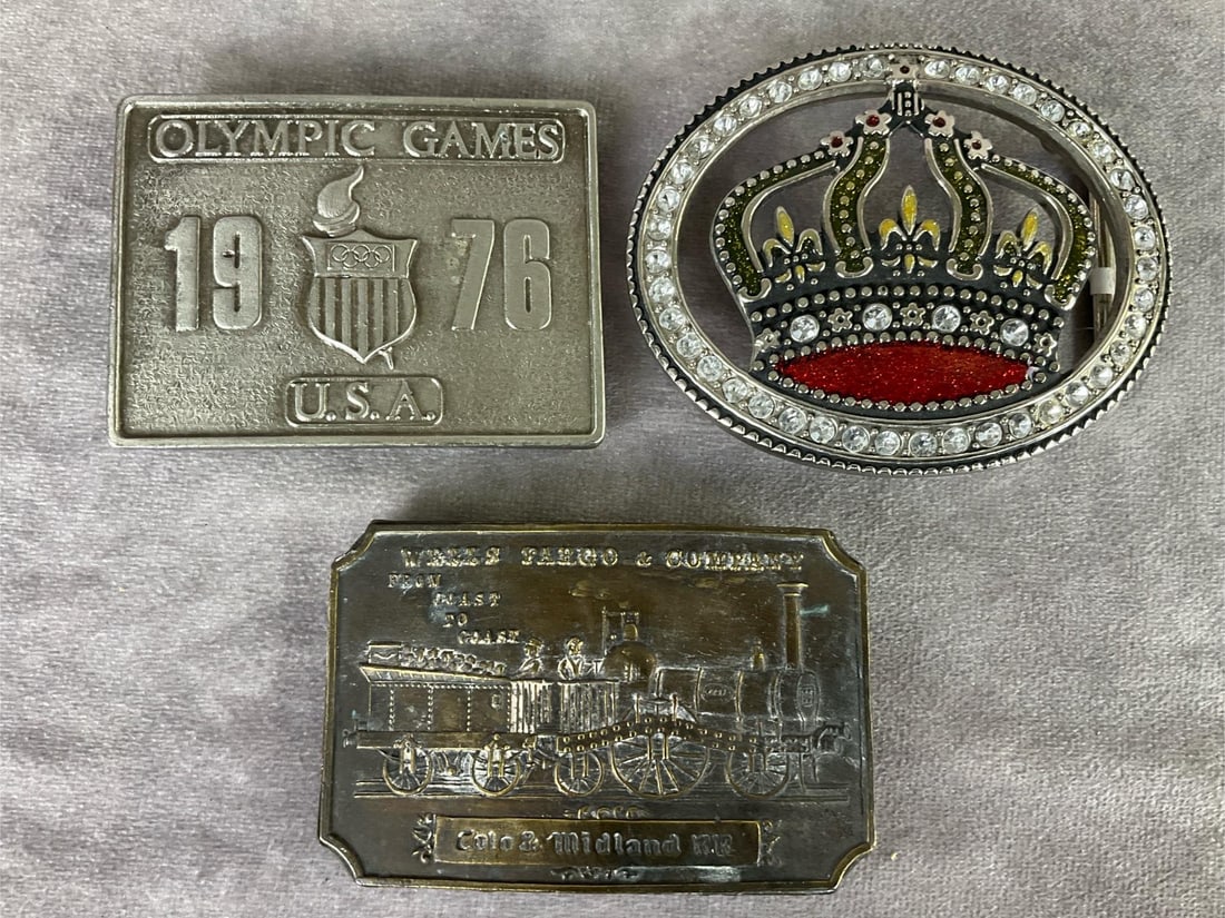 Belt Buckles: 1976 Olympic Games by Bergamot Brass Works, unmarked rhinestone crown, and Tiffany Studio brass Wells Fargo and Company buckle. Some tarnishing but overall good condition. Wells Fargo is 3.5 inches wi