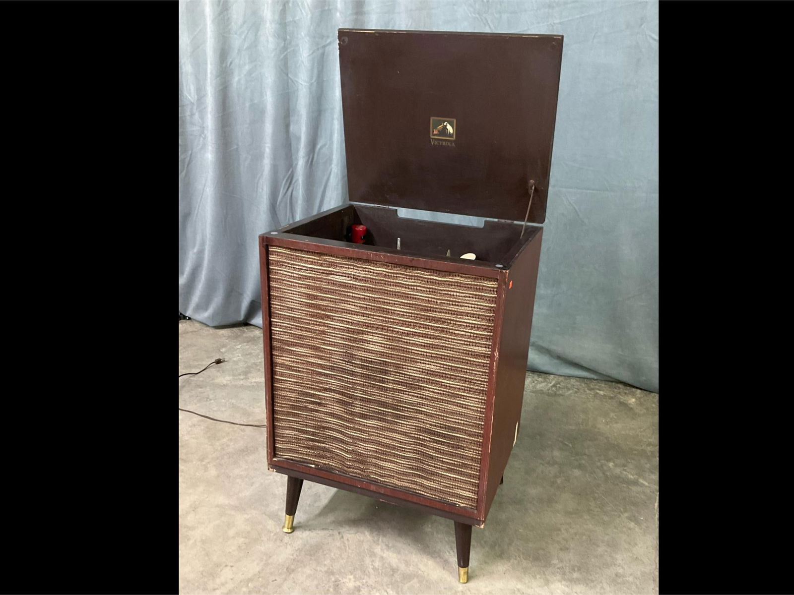 Victrola Model HFP Record Player: The player does power on and spin. Includes red Bakelite adapter. Speaker grille is in decent condition. Missing one brass ferrule, and the bottom cap off another. Speaker wire is cut. Some veneer los