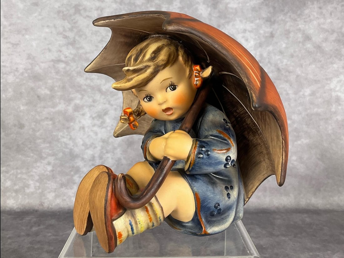 Umbrella Girl: Hum 152/0 B. TMK 4. Height of 4.75 inches. Mild crazing to glaze, overall good condition.