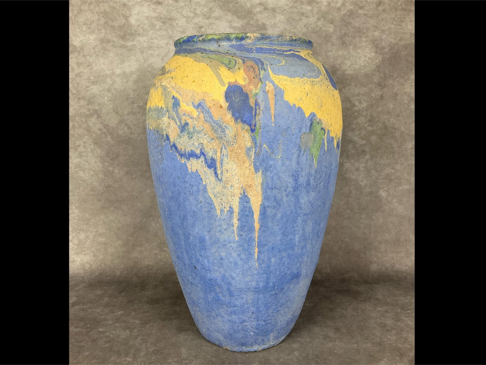 Ozark Roadside Tourist Pottery Vase: 14 inch tall vase in pale blue with pastel drip pattern in greens, blues, peach, and tan primarily on shoulders. Several small chipped areas with exposed concrete, chip in base, but overall good condi