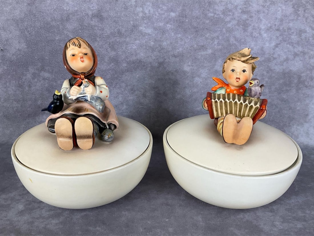 Two TMK 2 Boxes: Happy Pastime Box Hum III/69, and Lets Sing Box Hum III/110/0, both in the old style. Tallest 6.5 inches. Happy Pastime has mild crazing to lid base, as well as a small chip on rim as shown. Lets Sing