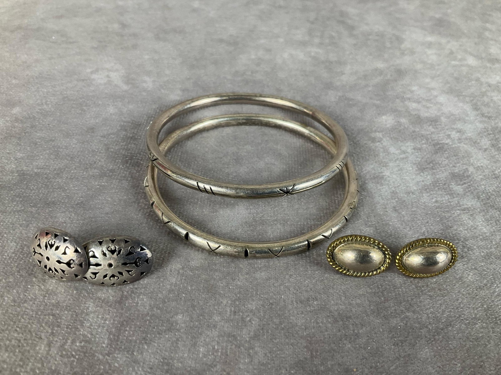 Mexican Sterling Jewelry: Two bangles and two pair of pierced post earrings. 1.20 ozt. One earring is missing a back. Bangles have 2.5 inch inner diameter.