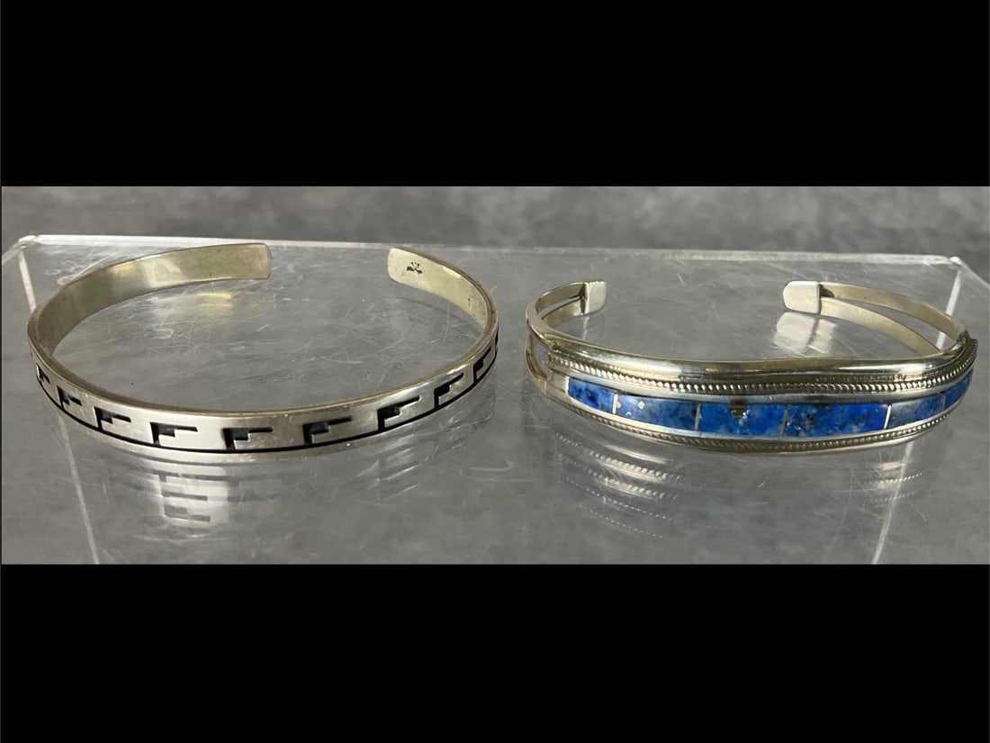 Native American Silver Cuff Bracelets: Cuff bracelet with black on silver appears to be a Hopi design. Unidentified hallmark, tests as silver. Slightly bent out of shape from use. Second bracelet is marked TB and Sterling. Good condition. 