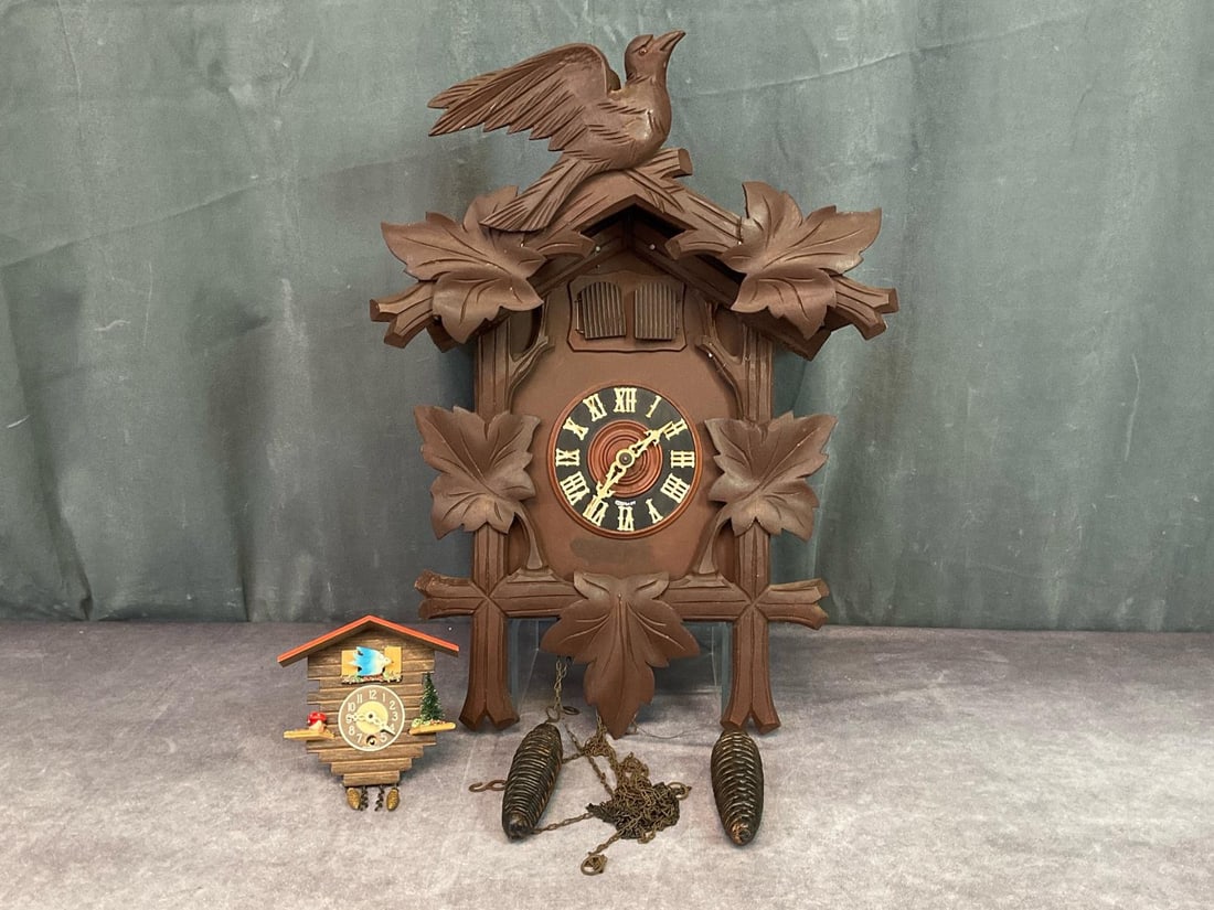 German Cuckoo Clocks: Larger clock is stamped Germany on front and back, two birds, missing pendulum and untested. Wear to edges of front decorative piece, 18 inches tall x 13.5 inches wide x 8 inches deep. Mini German clo