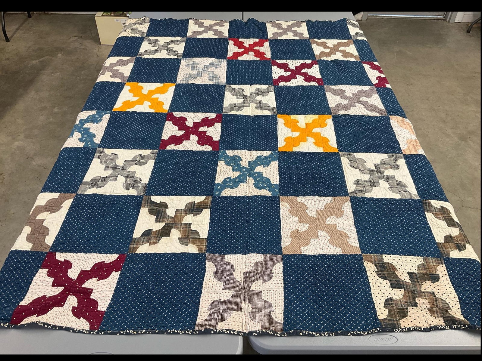 Hand Stitched X Quilt: Machine stitched edges. X pattern alternating with navy blue print squares. Some minor stains. 72 x 84 inches.