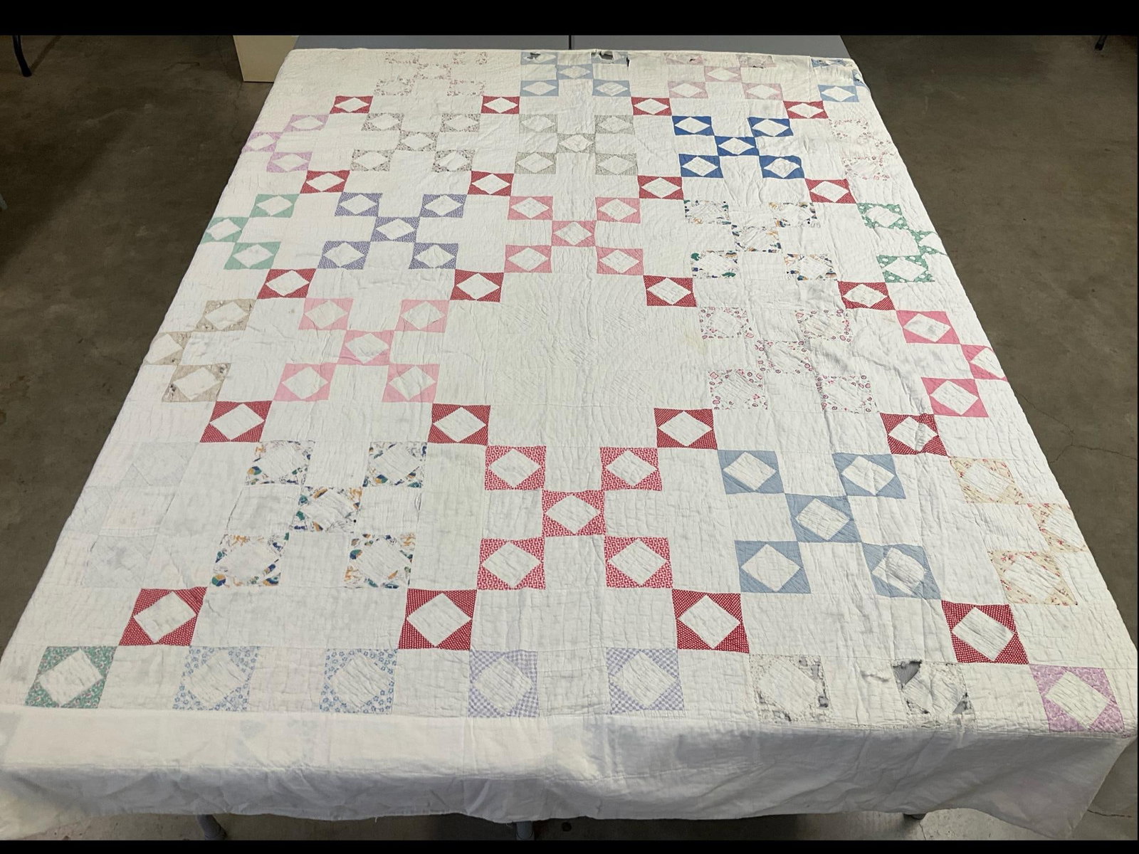 Hand Stitched Feedsack Quilt: Nine patch and diamonds. Machine stitched edges. There are some holes and significant tears. Quilt is thin and well washed. Some stains and yellowing at edge. 70 x 84 inches.
