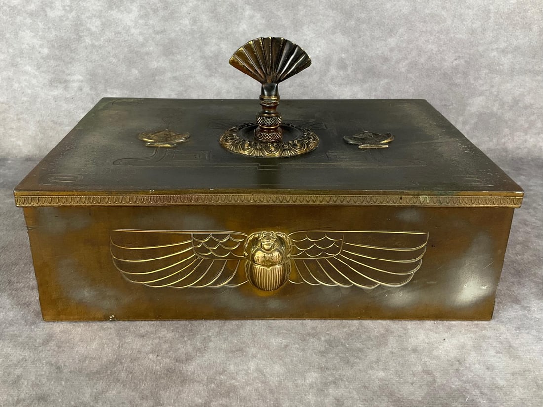 Benedict Karnak Egyptian Revival Brass Humidor: Scarab raised design on front. Lid has figures in relief as well as a handfan style pull which is possibly a non original enhancement. Karnak Brass mark on underside, and model number of 623. Scratche
