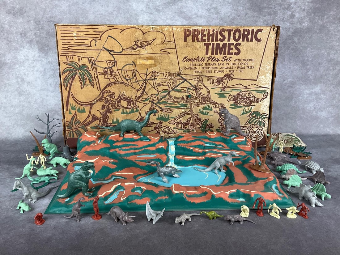 Prehistoric Times Play Set: By Marx Toys, Series - 1000, No. 3390. With original box, molded plastic base, prehistoric animals and cavemen figures,as well as trees and plants. Booklet present but in poor condition. Terrain base