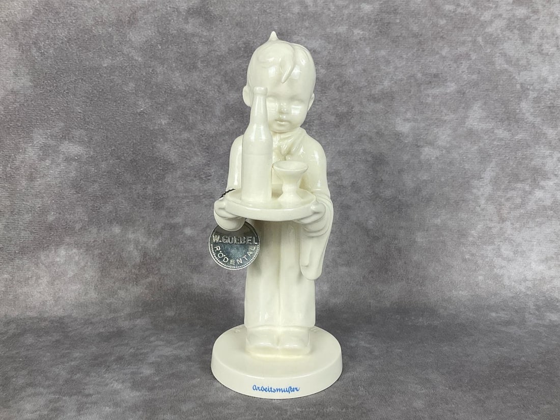 The Waiter - Arbeitsmuster: Hum 154/0 in white overglaze with blue decal of script Arbeitsmuster on bottom and metal medallion that reads W. Goebel Rodental/Arbeitsmuster attached. No copyright date or trademark present. Handwri