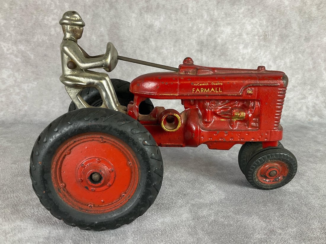 Arcade Cast Iron Farmall Tractor Toy: McCormick Deering Farmall in gold lettering on each side. An Arcade Toy Made in USA decal on axle. Front tires are marked Arcade Toys as well. Some wear around the wheels, minor rust to farmer. Some m