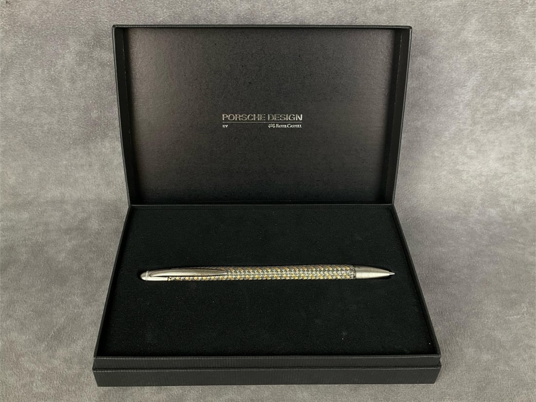 Porsche Design Mechanical Pencil: Stainless steel silver and goldtone weave pencil designed by Porsche and made in Germany by Faber - Castell. Length of 6 inches. Mild tarnish to lapel clip and pencil head, otherwise good condition wi