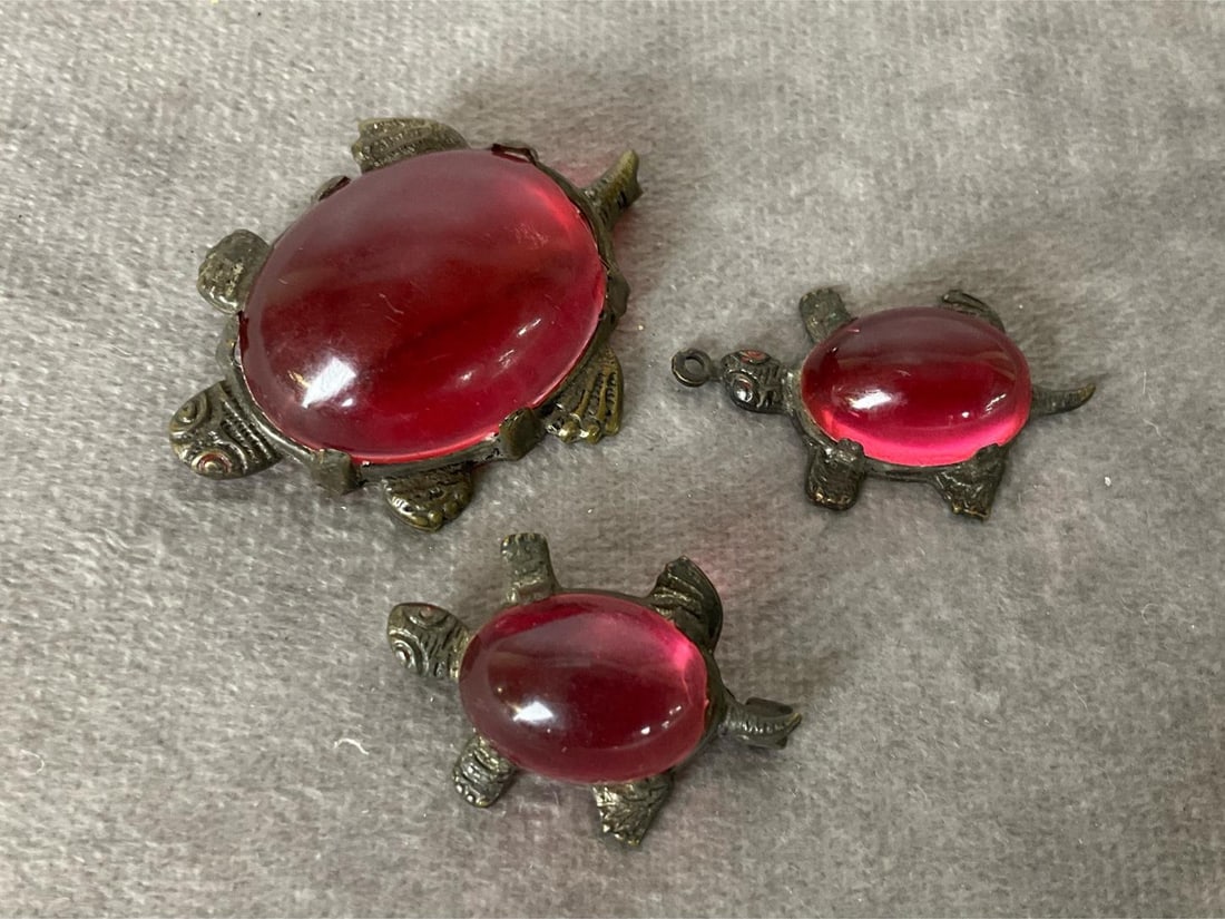 Watermelon Pink Jelly Belly Turtle Jewelry: 1940's-1950's. A large and small pin with matching pendant. Traces of red paint around the eyes. Largest brooch is missing a piece of lucite from the back edge. Pin stem is rough. The pin is 1 inch wi