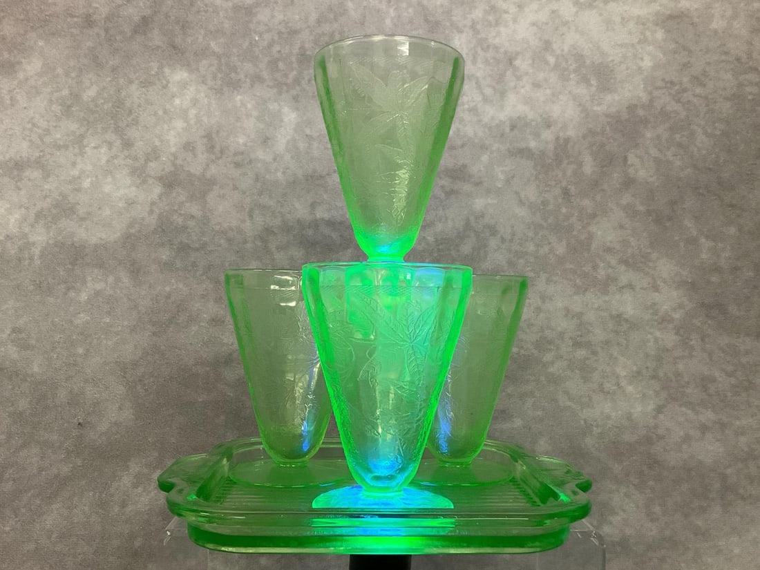 Jeanette Uranium Depression Glassware: In the Floral Green pattern. All pieces fluoresce under ultraviolet light. Four 4 inch footed juice glasses and a 7.5 inch handled square tray. One glass has a tiny chip on the rim, all other pieces i