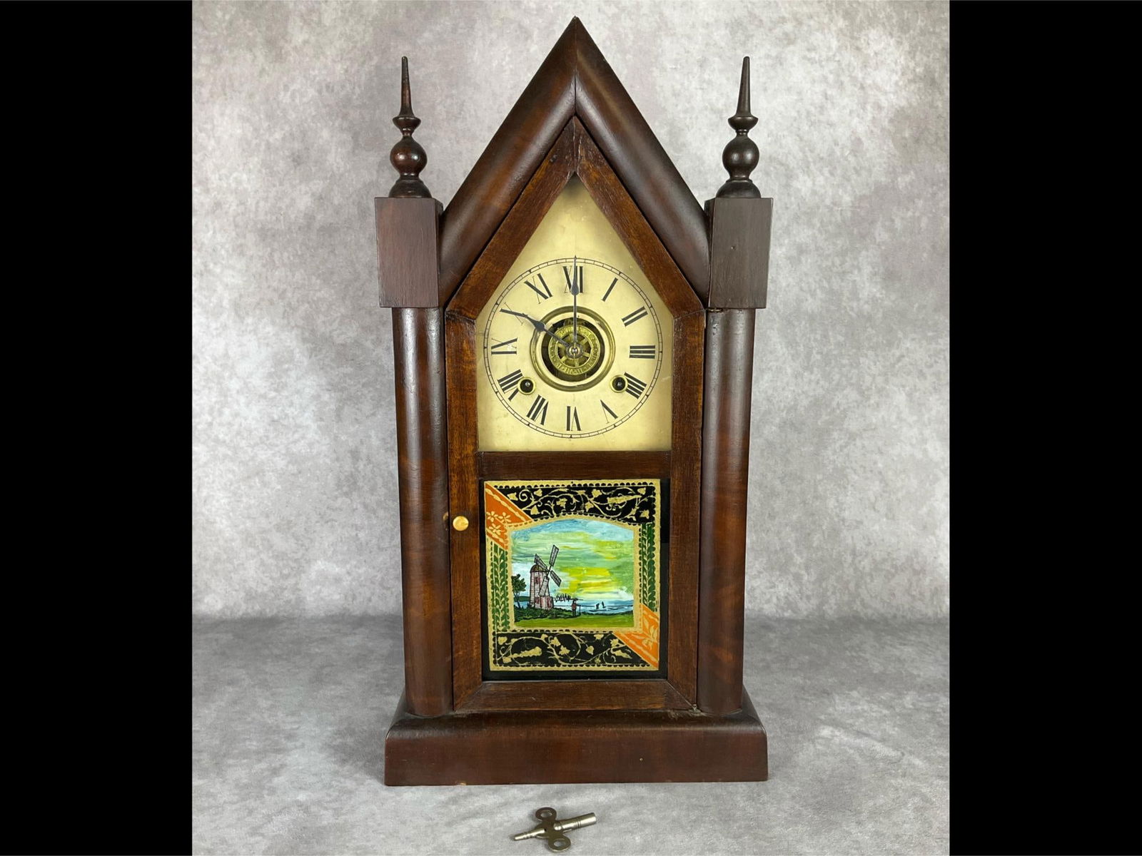 New Haven Clock Co. Steeple Clock: Late 19th century wood case clock. Original clock face and label behind workings. Glass front has been repainted. 20.5 inches tall x 10.75 inches wide. Winds and chimes but not guaranteed to run. Repl