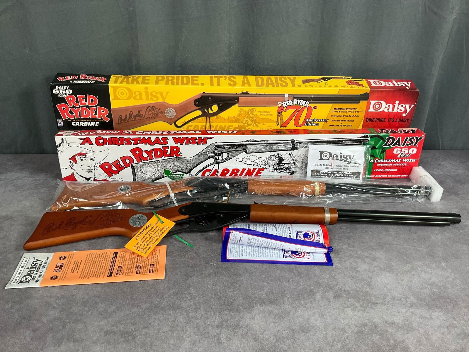 Two New Daisy BB Guns: 70th anniversary edition and a Christmas Wish edition. Both new in box, cocking levers still zip tied, and original papers. 37 inches long. Untested.