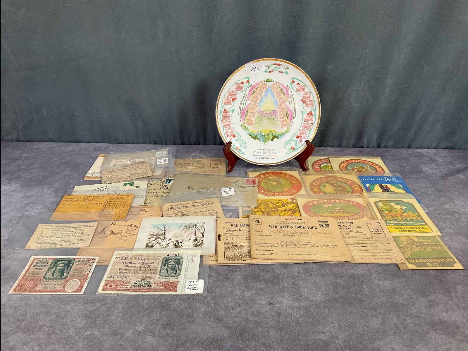 Virginia Interest & Military Ephemera: 1911 Buchanan, Virginia Clore Drug Company calendar plate, 8.25 inches in diameter. Wear to graphics and remnants of sticker stuck to top. Military ration books from Fig, NC. Other military ephemera. 