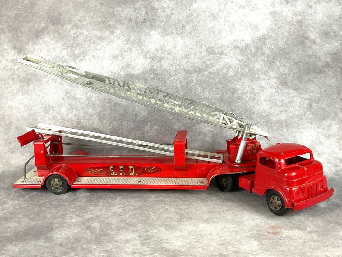 Structo Metal S.F.D. Fire Truck: Circa 1960, pressed steel. Hydraulic operated. In good condition with mild scratches and light rust. Measures 29 inches long.