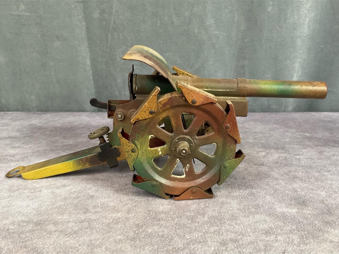 German Howitzer Toy Gun: Unmarked German pre war camouflage metal toy gun with firing mechanism. Adjustable dial for firing angle. Locking pin for firing mechanism does not hold hammer back. Some rust present on under side. 1