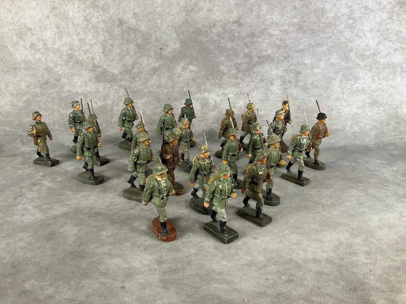 Elastolin Marching German Soldiers: Thirteen German, American, British soldiers marked Elastolin, Lineol, and unmarked. Cracking, paint loss, repainted. Tallest measures 3 inches.