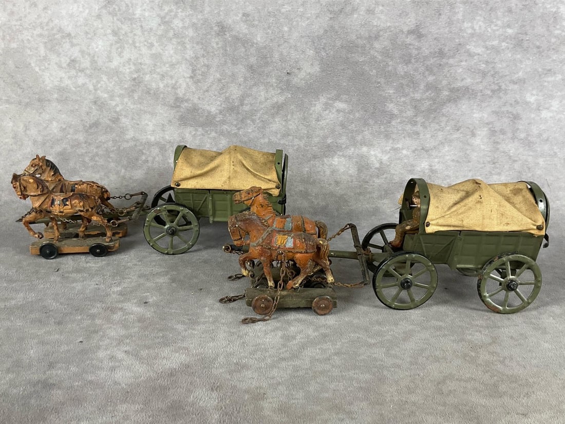 Tin Toy Covered Wagons: Group of two with two sets of horses. One soldier. Wagons have rust, stained canvas and loose wheels. Horses have paint loss, and are in poor to fair condition. Both measure 8.5 inches long.