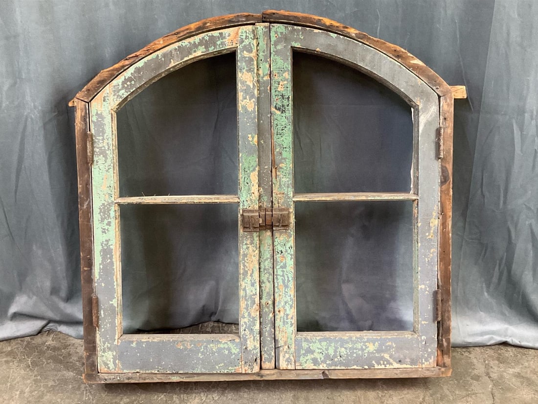 Architectural Salvage Window: Turn of the century arched top window with shutter doors. Original cast Iron latch and hardware. Interior shelves have been added. Paint is chipping off. Joints are a little loose but still held toget