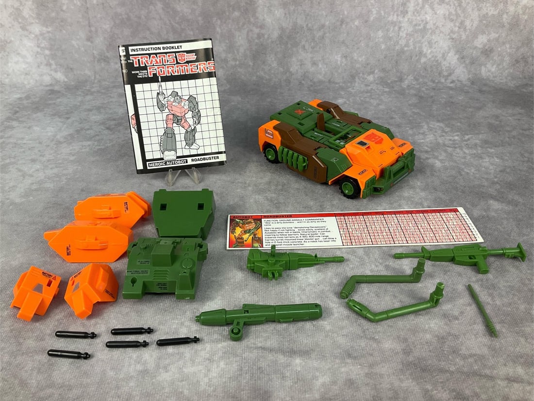 1984 Roadbuster Transformer: Made by Hasbro in Japan. Complete with instruction booklet, tech spec card, accessories, and weapons. Missing decoder. Good condition but does have minor wear to decals. Transformer measures 5 inches