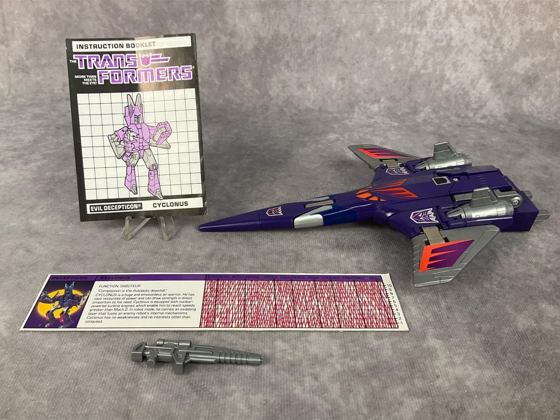1986 Cyclonus Transformer: Made by Hasbro in Japan. Complete with instruction booklet, tech spec card, and weapon. Missing decoder. Good condition. Transformer measures 8.75 inches long x 6 x 1.25 inches tall.
