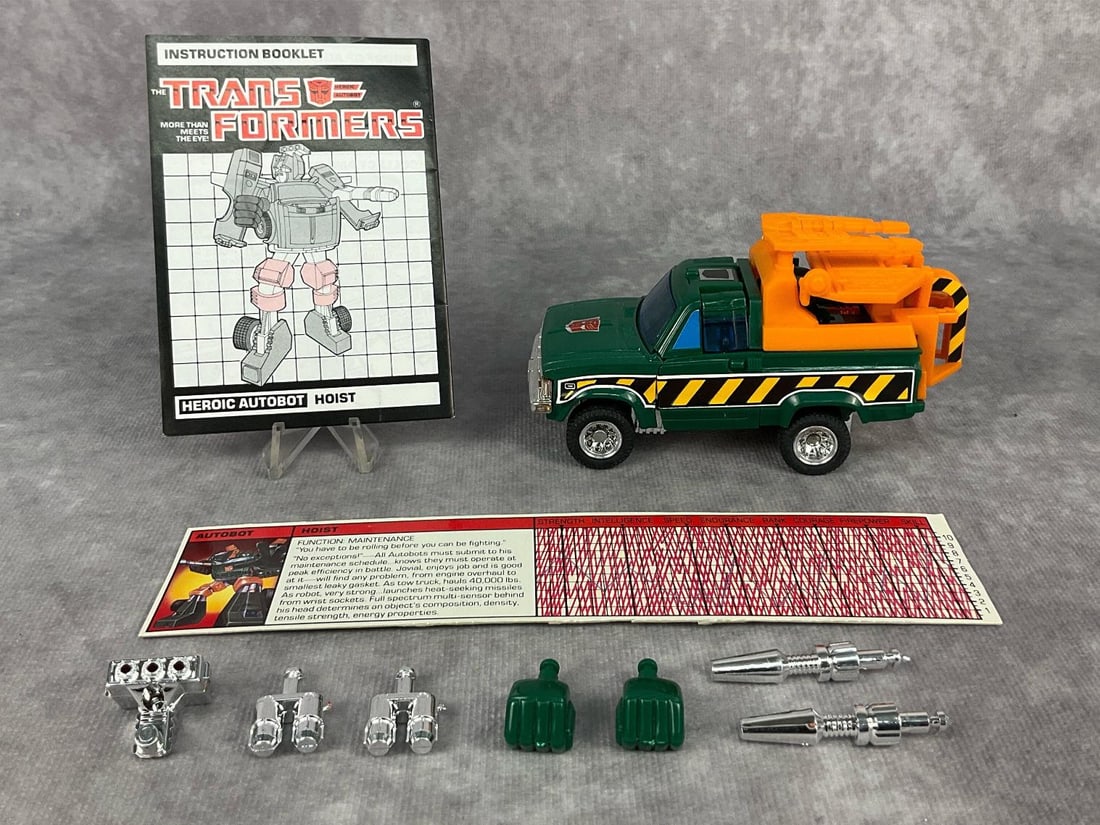 1985 Hoist Transformer: Made by Hasbro in Japan. Includes instruction booklet, tech spec card, accessories, and weapons. Missing decoder. Good condition but side decals are starting to peel. Transformer measures 4.5 inches l