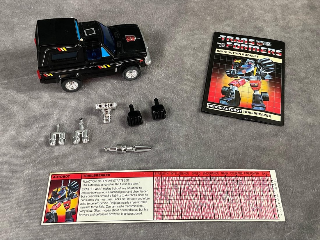 1984 Trailbreaker Transformer: Made by Hasbro in Japan. Complete with instruction booklet, catalog, tech spec card, and weapons. Missing decoder. Good condition, but does have minor wear to decals. Measures 4 inches long x 2 x 2 in