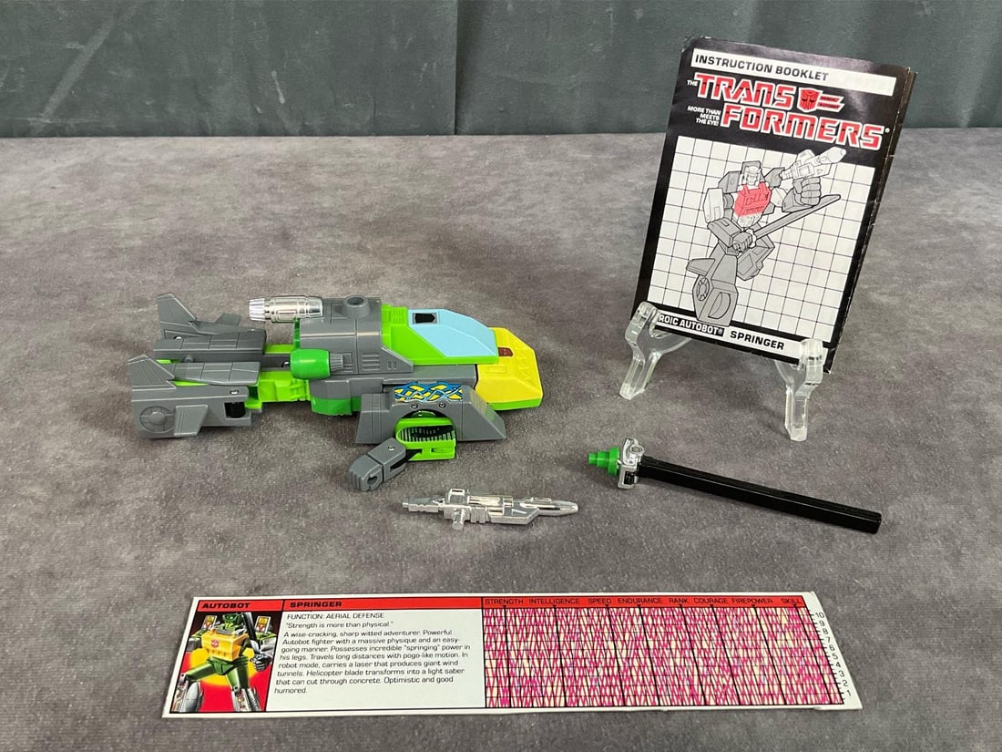 1986 Springer Transformer: Made by Hasbro in Japan. Complete with instruction booklet, catalog, tech spec card, and weapons. Missing decoder. Good condition, but does have minor wear to decals. Measures 5.5 inches long x 3 x 2