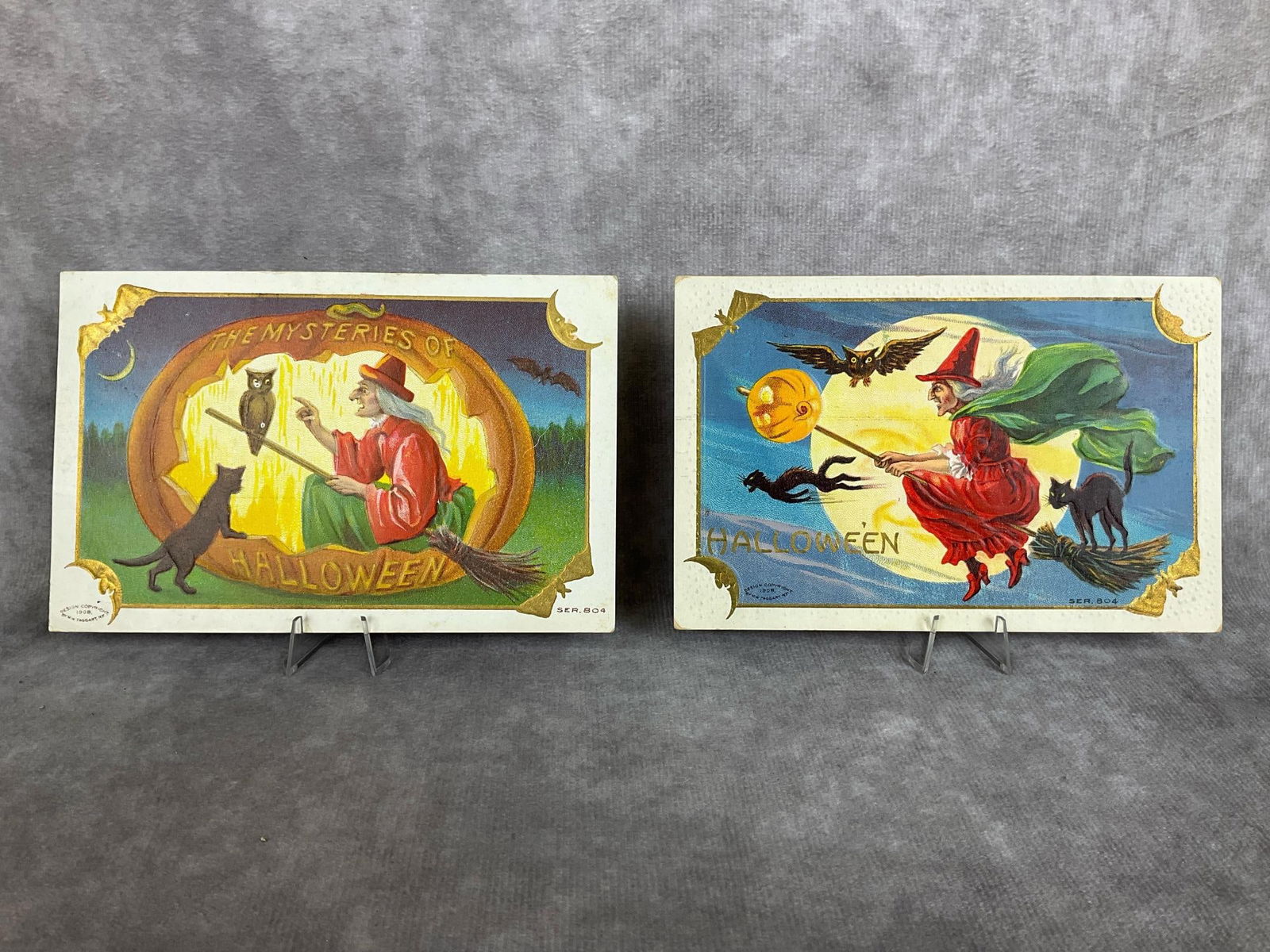 WM Taggart Halloween Postcards: Two 1908, series 804, Halloween postcards. Marked in lower left corner WM Taggart. Bat and moons in each corner, cards are embossed. Soft corners, foxing on back, and one card has discoloration on cor