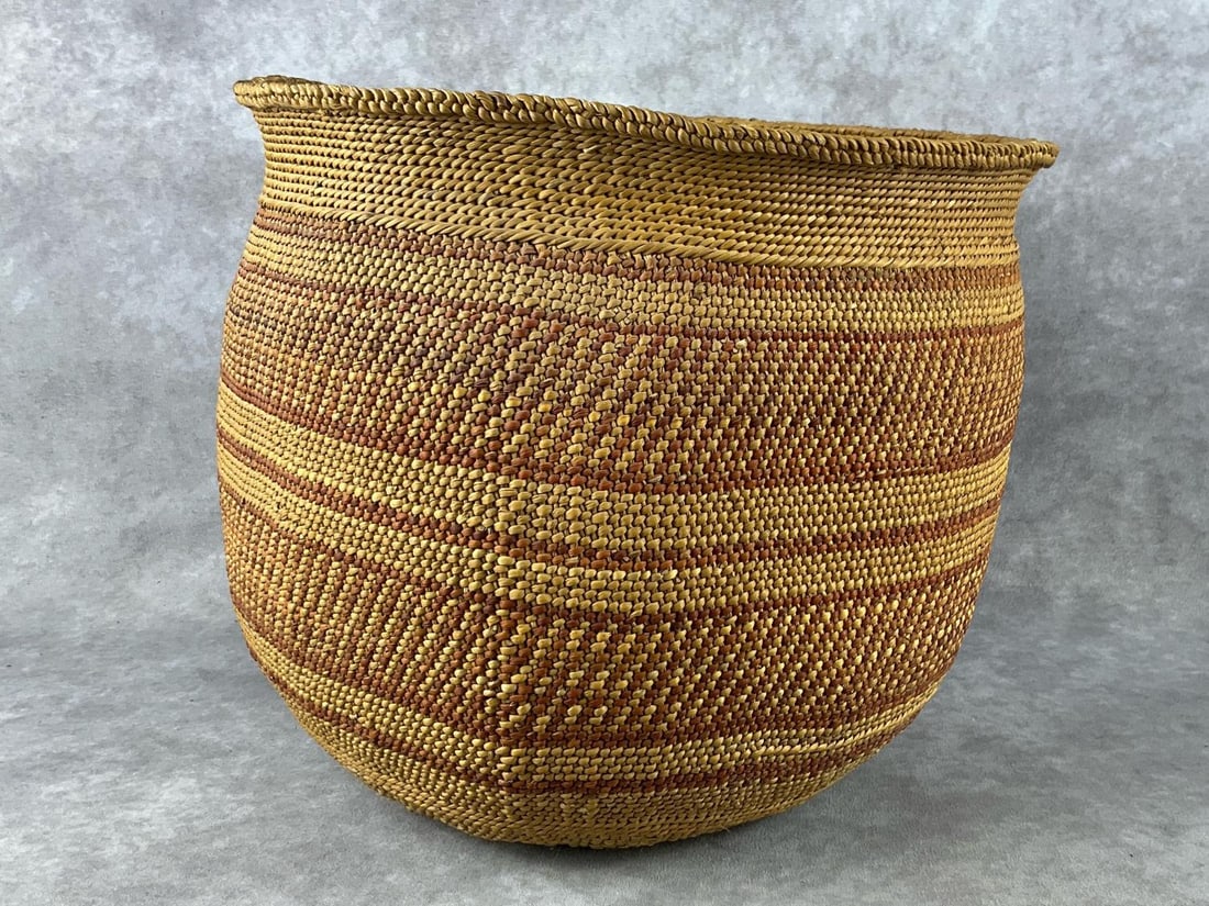 Woven Trade Basket: Large amber and brown woven trade basket. In good condition. Measures 12 inches in diameter x 11 inches tall.