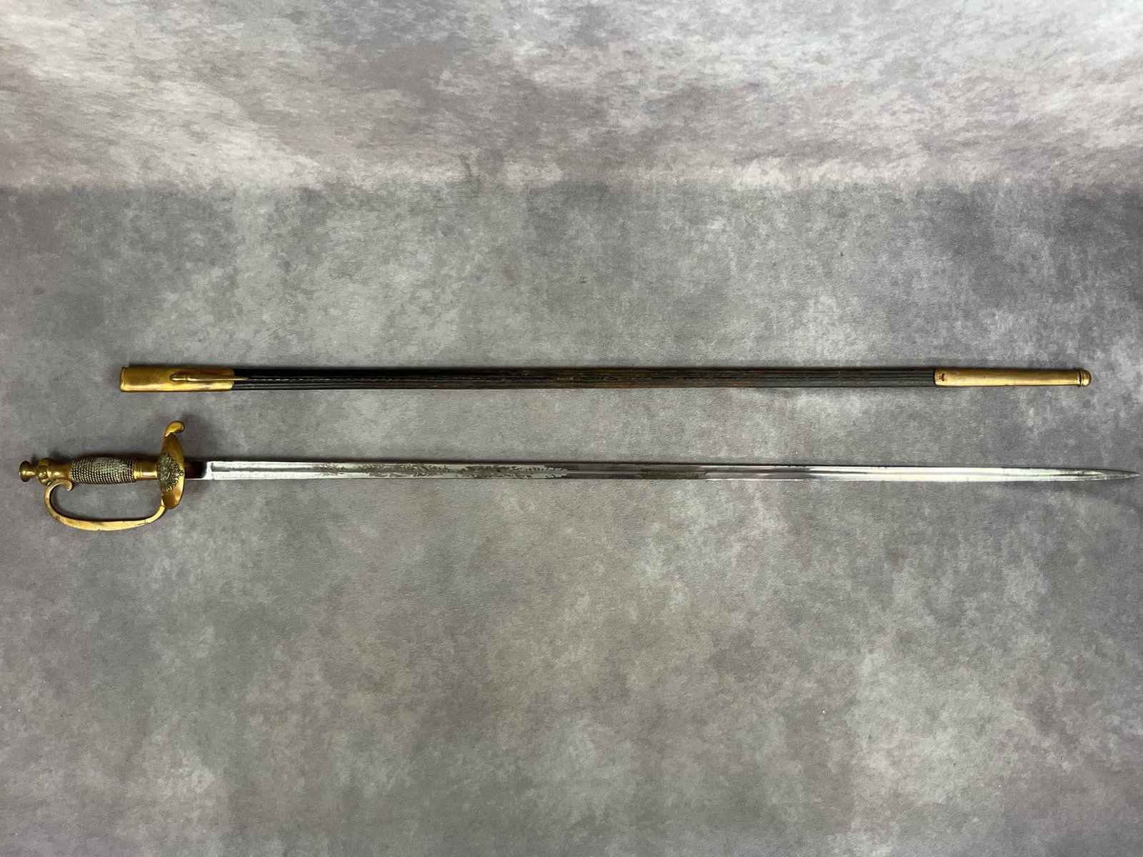 WWI Postal Officer Dress Sword: WWI era German poster officer dress sword with leather wrapped scabbard with brass throat and tip. Engraved blade with the name Feldstein and Berger on the edge. Makers mark is located under clamshell